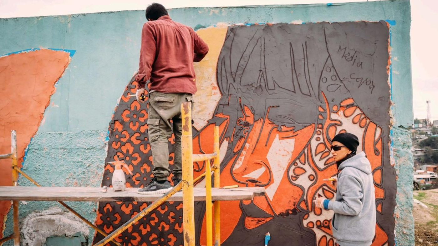 Personas pintan un muro desde un andamio