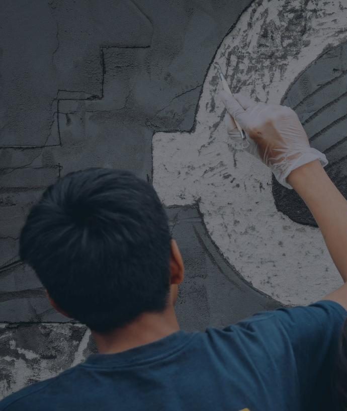 Una persona con guante talla un diseño en un muro